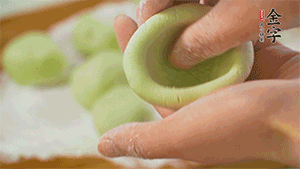 將均分的艾草面團(tuán)搓成圓，挖一個(gè)窩，放入餡心，再搓成圓。