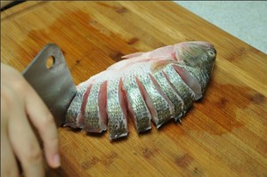 將鱸魚清洗干凈，從脊椎處切斷至腹部，腹部保留1cm左右不要切斷。