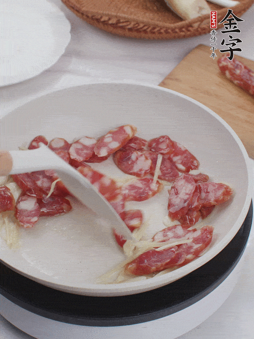 油溫3成熱時(shí)，下姜絲、蒜片、香腸炒出油脂。