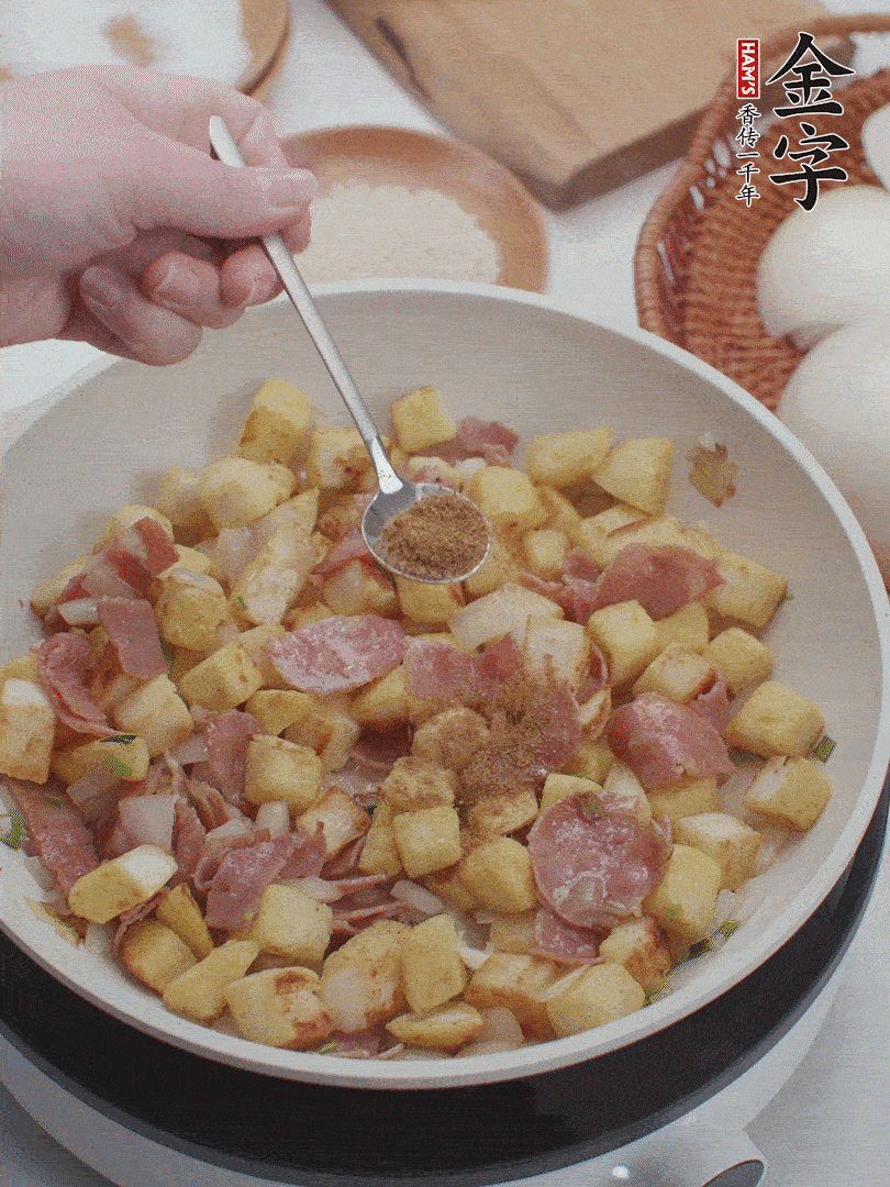 起鍋少油，煸香洋蔥丁、蔥白，加入金字培根火腿翻炒幾下，再加入饅頭丁、1小勺孜然粉、少許鹽翻炒均勻并鋪平。