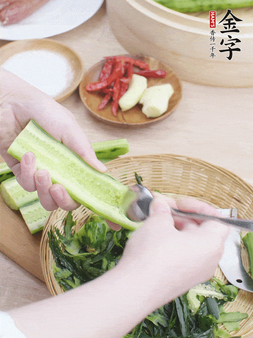 黃瓜削皮，對半切開，勺子挖去內(nèi)瓤，斜刀切片。青蒜斜刀切段。